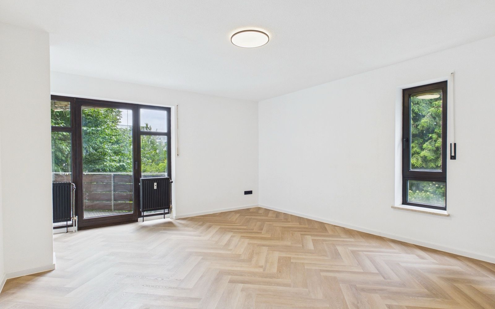 Dasselbe Wohnzimmer frisch saniert, leer, mit hellem Fischgrätparkett