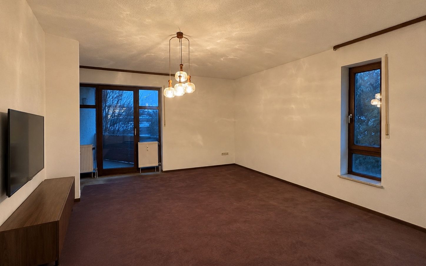 Leeres Wohnzimmer mit altem Teppichboden, Zustand vor der Sanierung